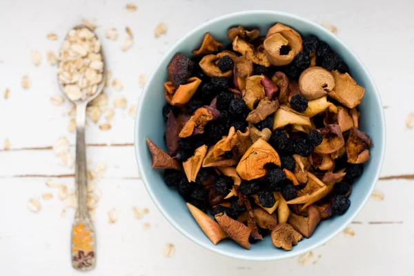 One tablespoon of oatmeal is a white wooden background near blue — Stock Photo, Image