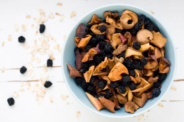 Blue plate with dried apples and berries and oatmeal on a white — Stock Photo, Image