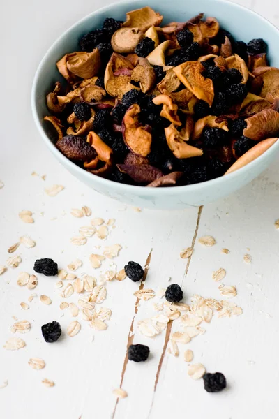 Blue plate with dried apples and berries and oatmeal on a white — Stock Photo, Image