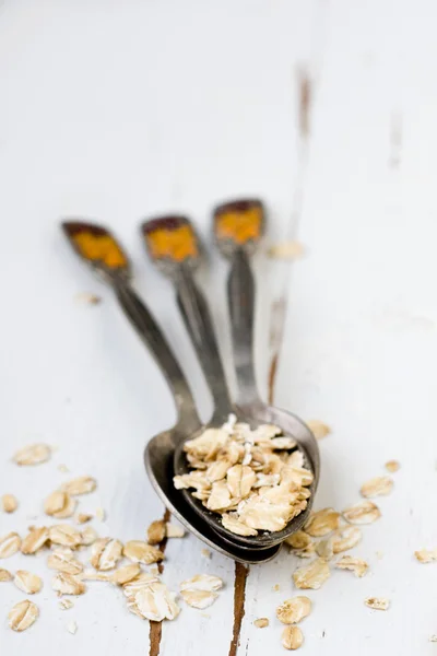 Tres cucharadas de avena sobre un fondo de madera blanca . —  Fotos de Stock