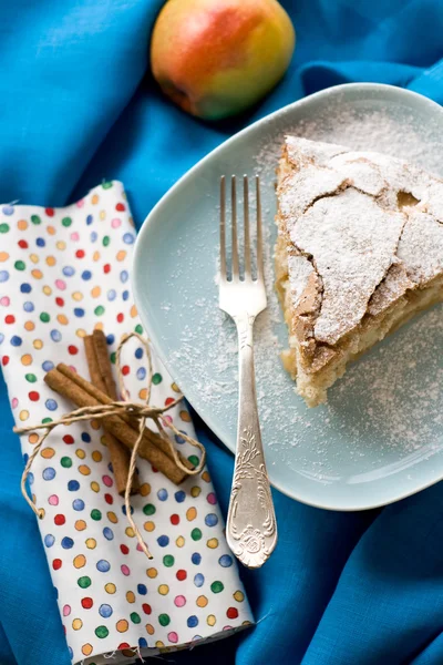 Un pezzo di torta di mele sdraiato sul piatto blu, mela, bastoncini di cannella — Foto Stock