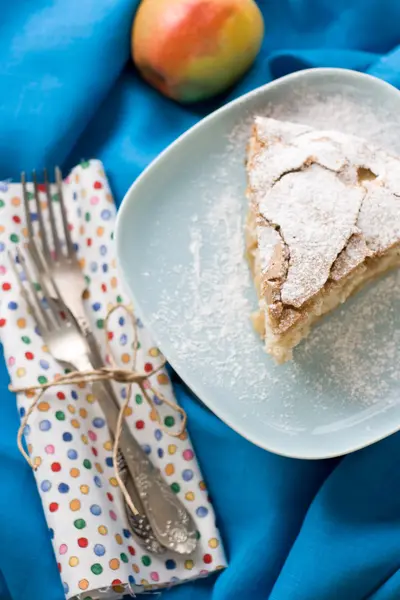 A piece of apple pie lying on blue plate, apple, fork on a color — Stock Photo, Image