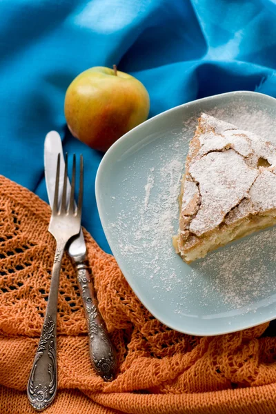 Кусок яблочного пирога лежит на голубой тарелке, яблоко, коричные палочки — стоковое фото
