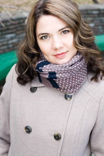 Portrait of a young beautiful curly brunette in beige coat and s — Stock Photo, Image