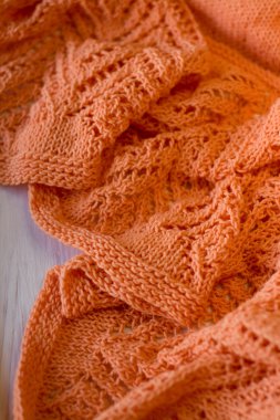 Beyaz ahşap zemin üzerinde parlak turuncu örme şal