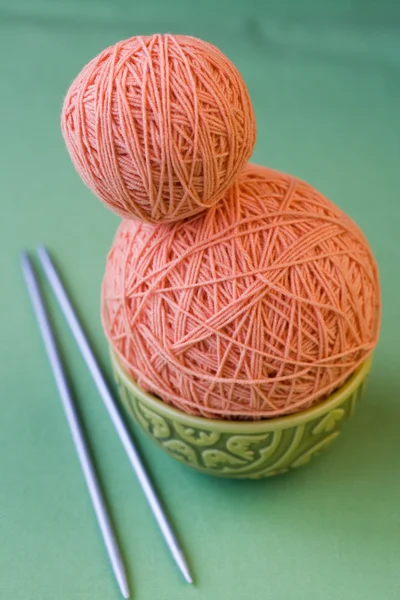 Two balls of pink yarn and knitting needles on a National Turkis — Stock Photo, Image