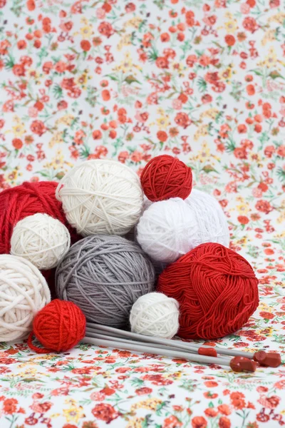 Um monte de bolas brilhantes de tricô no fundo de um flo vermelho — Fotografia de Stock