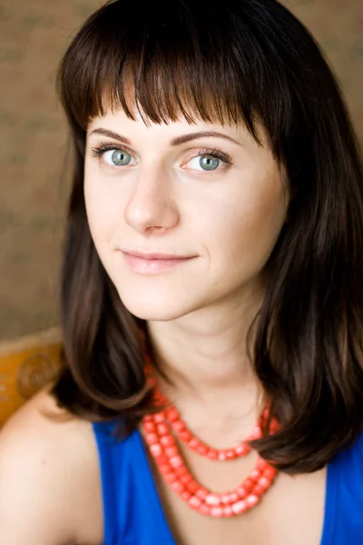 Portrait of a beautiful young brunette with red beads — Stock Photo, Image