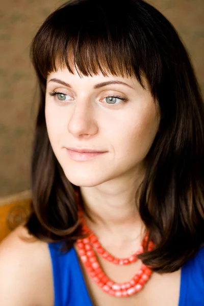 Portrait of a beautiful young brunette with red beads — Stock Photo, Image