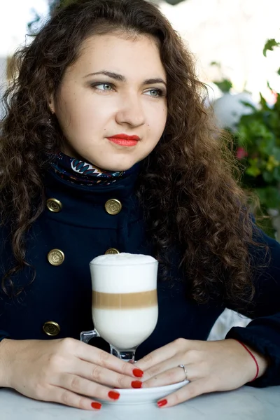 Young beautiful brunette with a delicious latte in a street cafe — Stock Photo, Image