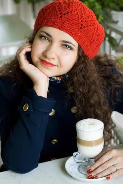 Młoda brunetka z pyszne latte w kawiarni ulicy — Zdjęcie stockowe