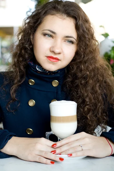 Mladá krásná brunetka s lahodné latte v pouliční kavárně — Stock fotografie