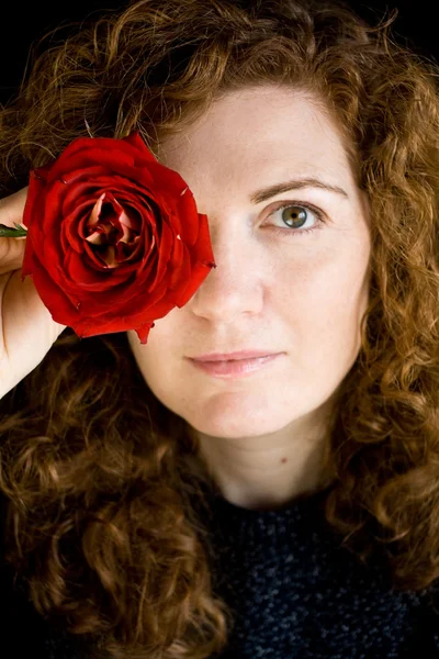 Portret piękny młody rude kręcone Red rose w ręku — Zdjęcie stockowe