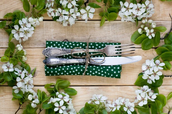 Fork and knife lying on a wooden background among the branches — Stock Photo, Image