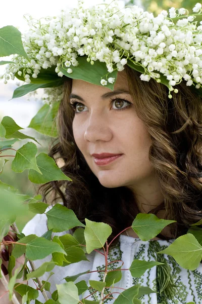 Portrait of a young beautiful in traditional Ukrainian embroidered shirt and a wreath of lilies of the valley on the head — Stock Photo, Image