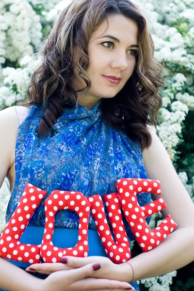 La chica en un vestido azul sosteniendo una tela textil letras — Foto de Stock