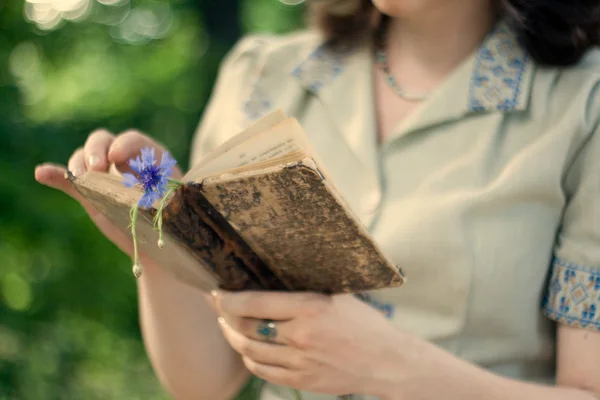 Ein junges Mädchen in einem Vintage-Kleid hält ein altes Buch — Stockfoto