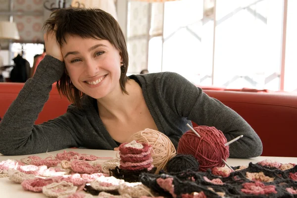 Jeune fille souriant et crochet écharpe avec des fleurs — Photo