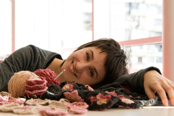 Jeune fille souriant et crochet écharpe avec des fleurs — Photo