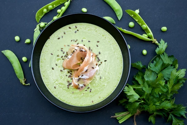 Sopa verde saludable con jamón y guisantes sobre un fondo negro — Foto de Stock