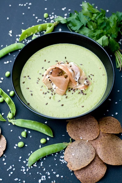 Sopa verde saludable con jamón y guisantes sobre un fondo negro — Foto de Stock