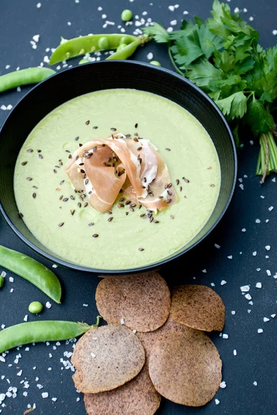 Sopa verde saludable con jamón y guisantes sobre un fondo negro — Foto de Stock