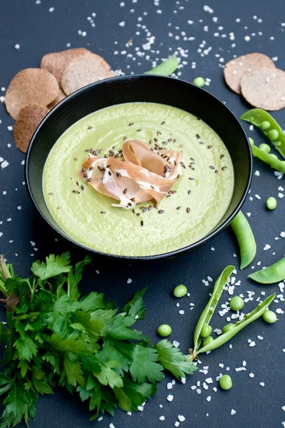 Friskt grön soppa med skinka och ärtor på svart bakgrund — Stockfoto
