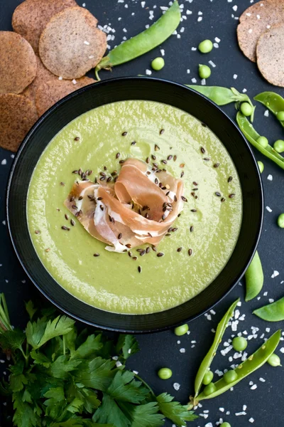 Sopa verde saludable con jamón y guisantes sobre un fondo negro — Foto de Stock