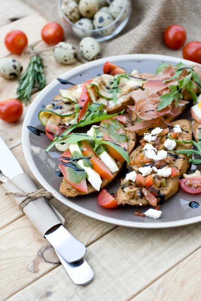 Viele leckere Bruschetta mit Käse, Tomate, Wachtelei, Schinken, s Stockbild