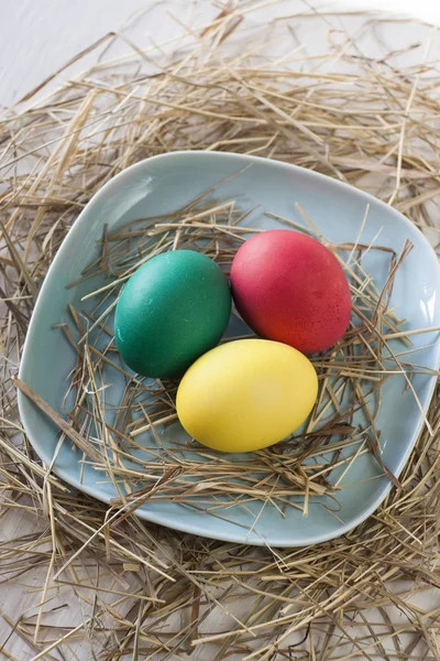 Huevos de Pascua en plato de paja sobre fondo blanco —  Fotos de Stock