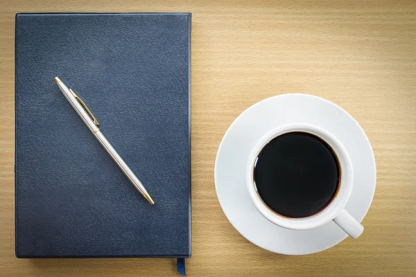 Café e caderno sobre mesa de madeira — Fotografia de Stock