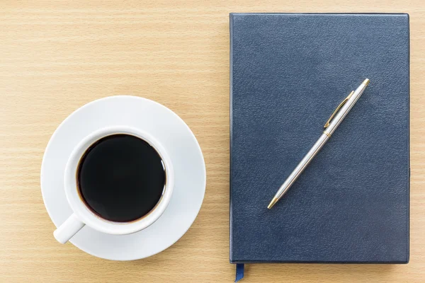 Café e caderno sobre mesa de madeira — Fotografia de Stock