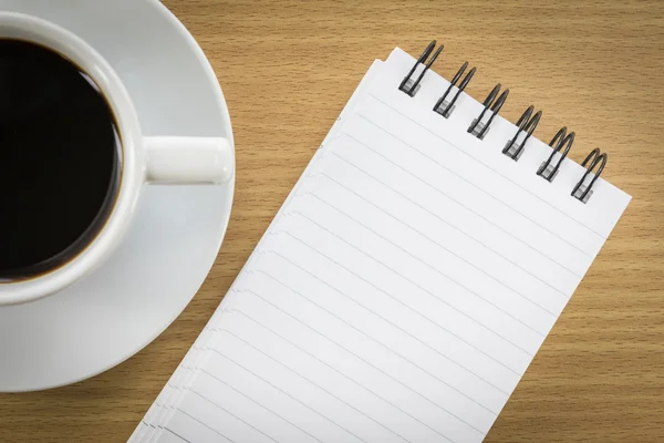 Café e bloco de notas na mesa de madeira — Fotografia de Stock