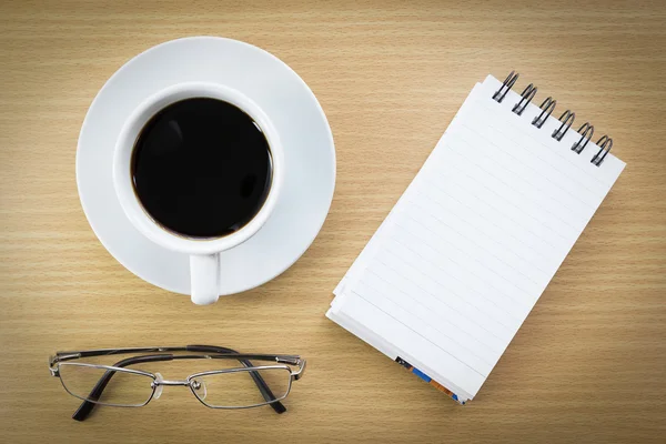 Coffee and notepad on wood table — Stock Photo, Image