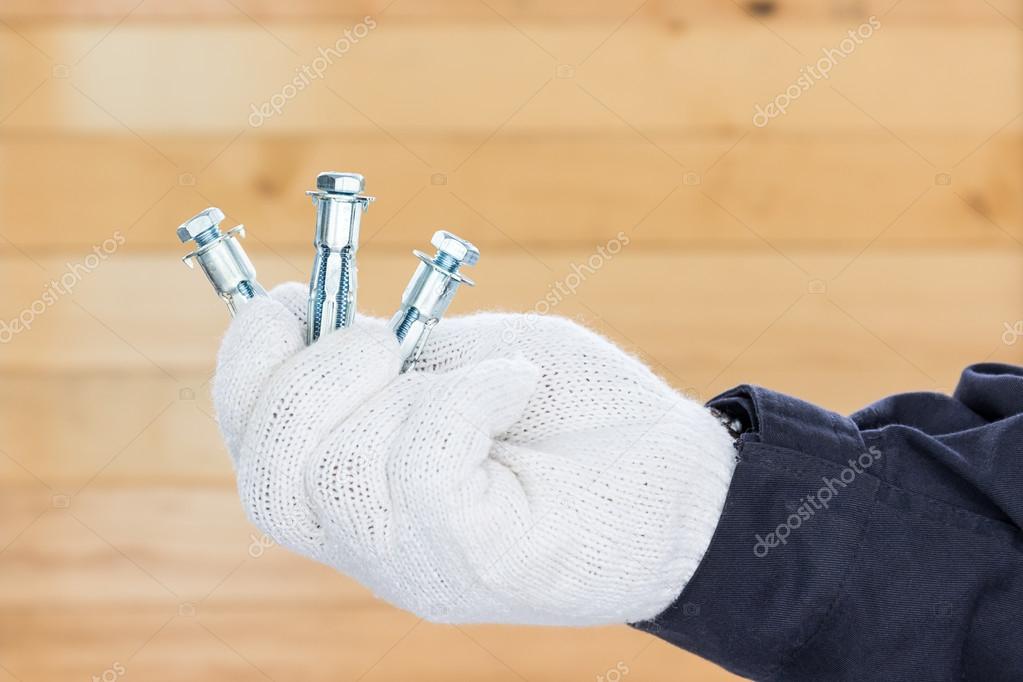 Hand in glove holding metal anchor bolt