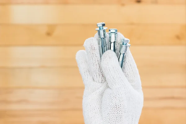 Hand i handske holding metall ankare bultar — Stockfoto