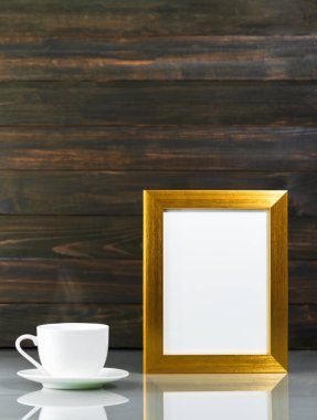 Resim, ahşap duvarlı masa üzerinde altın çerçeveli kahve fincanı ile taklit edilir.