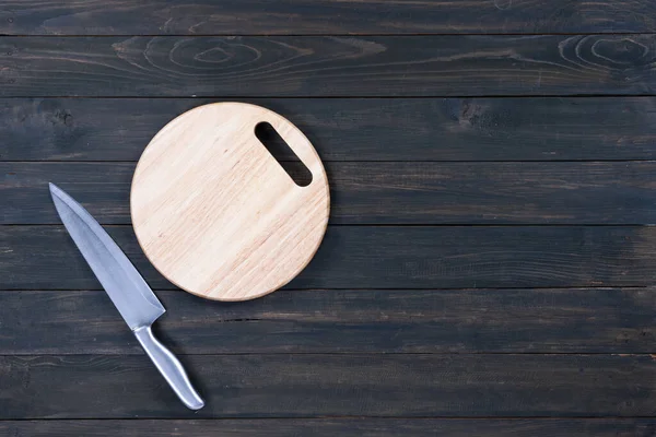 木製のテーブルの上のキッチンナイフと木製の丸い空のまな板を閉じる — ストック写真