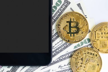Üst Manzara Bitcoins madeni parası ve 100 dolarlık akıllı telefon banknotları. Metal parlayan bitcoin şifreleme paraları ve Amerikan dolarını kapat