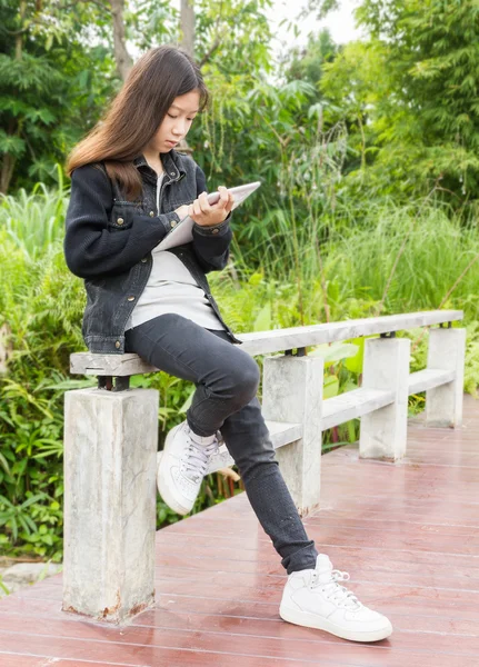 Una giovane ragazza che utilizza tablet computer nel parco — Foto Stock