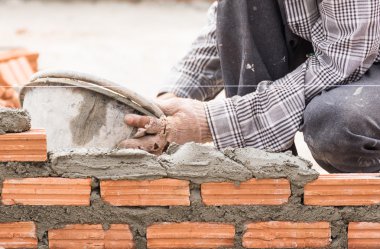 Bir tuğla duvar inşaat sitesinde çalışıyor çimento