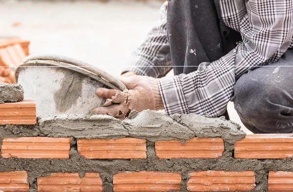 Maçon travaillant sur le chantier de construction d'un mur de briques — Photo