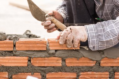 Bir tuğla duvar inşaat sitesinde çalışıyor çimento