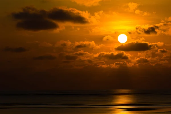 Dramatische zonsondergang achter de wolken boven de zee — Stockfoto