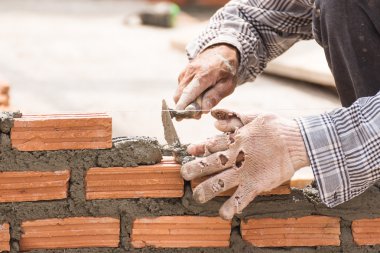 Bir tuğla duvar inşaat sitesinde çalışıyor çimento
