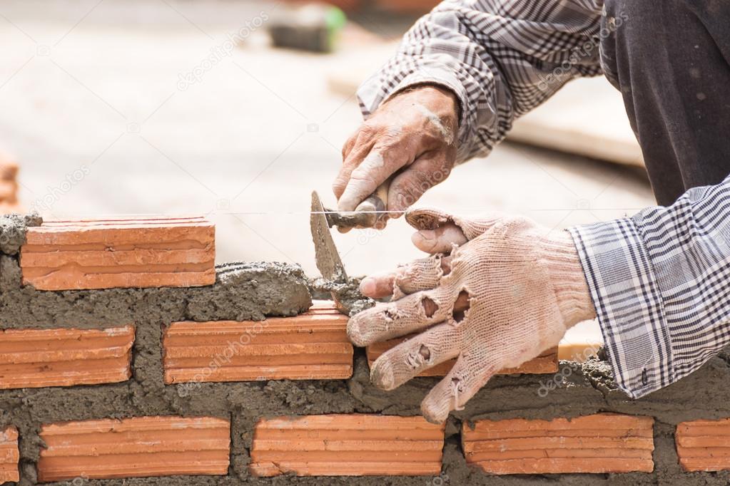 Bricklayer working in construction site of a brick wall