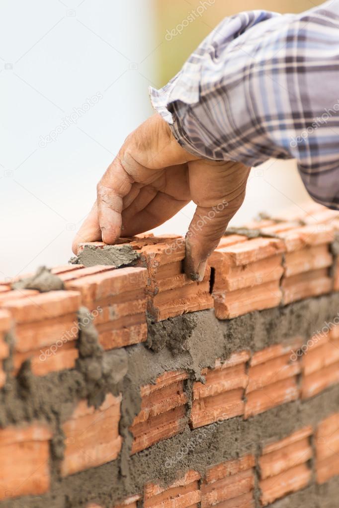 Bricklayer working in construction site of a brick wall