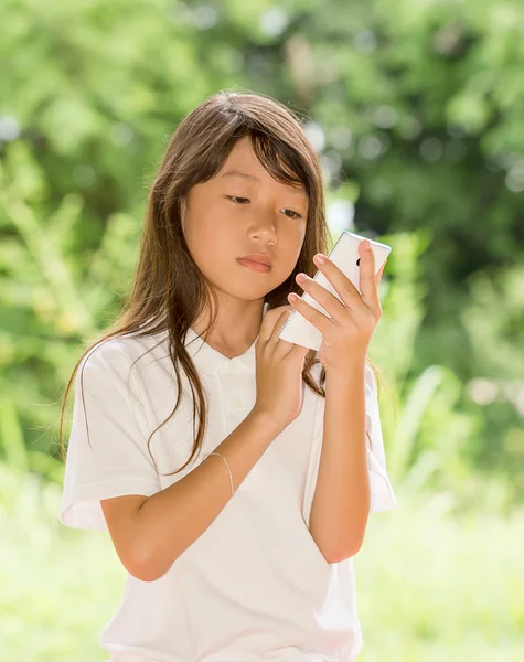 Έξυπνο τηλέφωνο χρήση Ασίας κορίτσι στον κήπο — Φωτογραφία Αρχείου