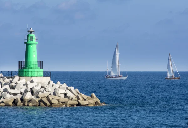 Lighthouse lined with sailboats — Stock Photo, Image