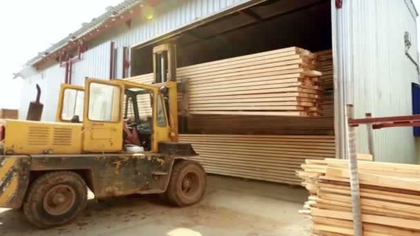 Zicht op de heftruck ladingen planken in magazijn — Stockvideo